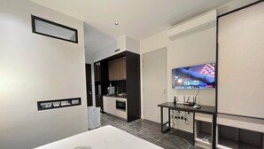 A modern hotel room with a large bed, a TV, a small kitchenette, and a bathroom visible through an open door. - SCARLETZ SUITES KLCC BY LLP (Kuala Lumpur)