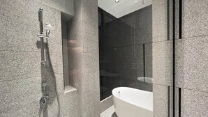 A modern bathroom with a freestanding bathtub, a glass-enclosed shower area, and granite tile walls. - SCARLETZ SUITES KLCC BY LLP (Kuala Lumpur)
