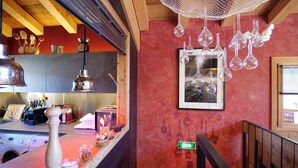 Une cuisine avec des poutres en bois, des ampoules suspendues et un tableau encadré au mur.