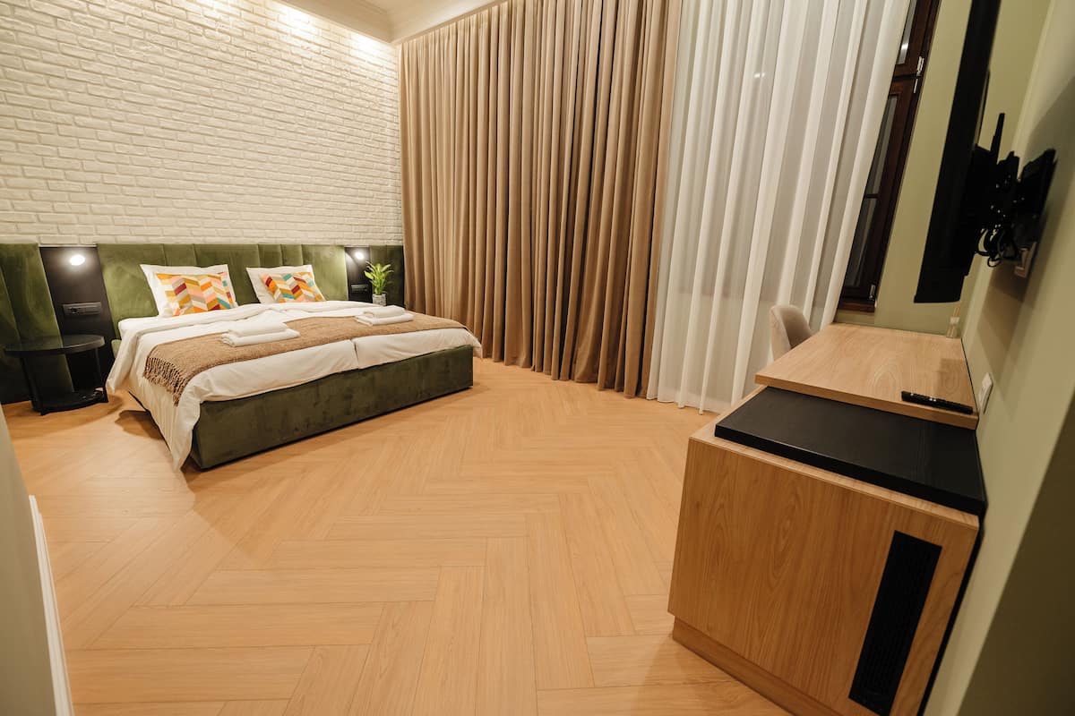 A modern bedroom with a large bed, a wooden desk, and a brick wall.