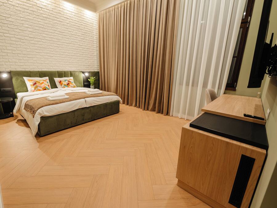 Quarto moderno com uma cama grande, uma escrivaninha de madeira e uma parede de tijolos.
