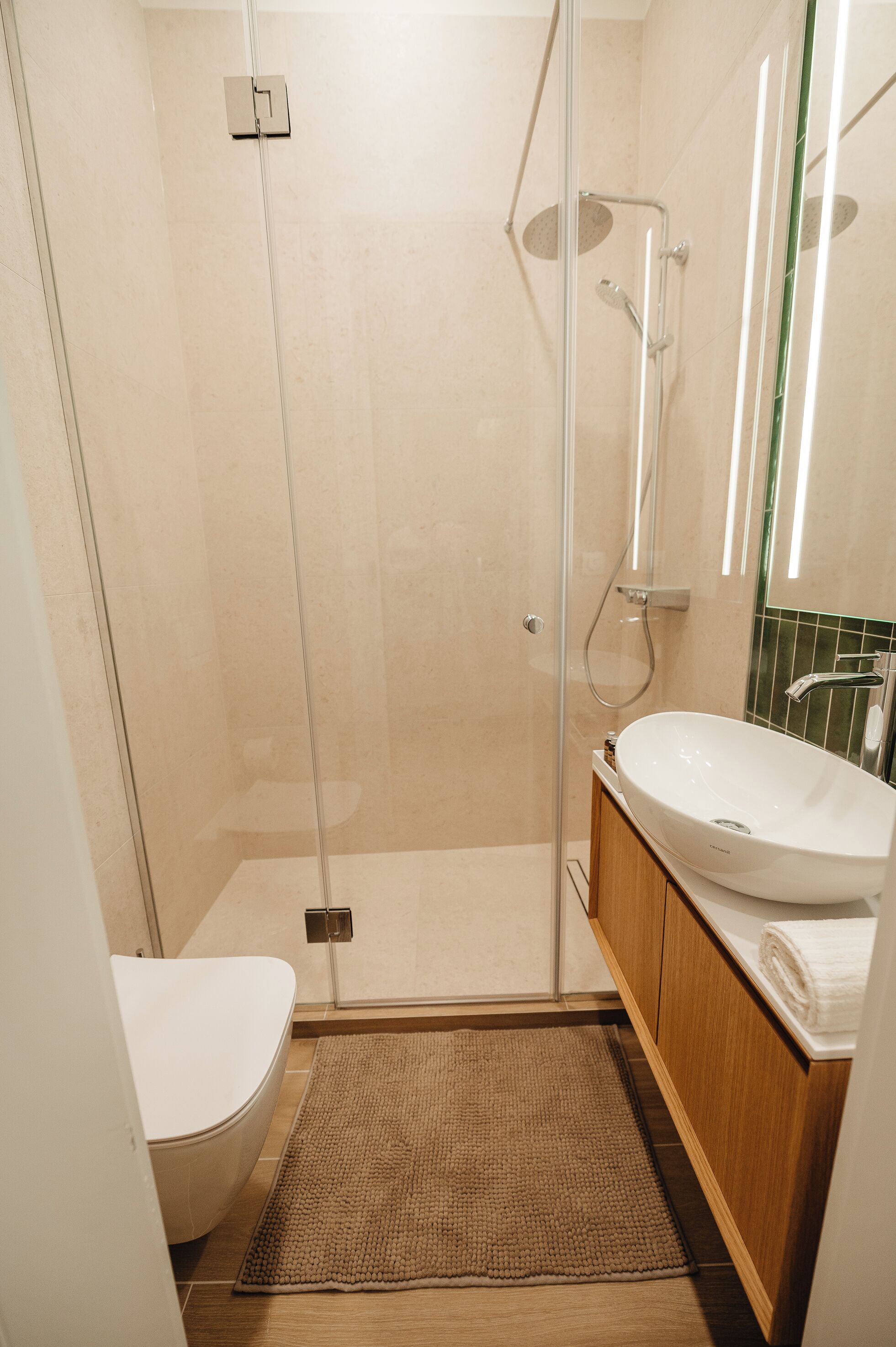 Une salle de bain moderne avec une douche à parois de verre, un lavabo blanc et un meuble-lavabo en bois.