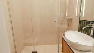 Une salle de bain moderne avec une douche à parois de verre, un lavabo blanc et un meuble-lavabo en bois.