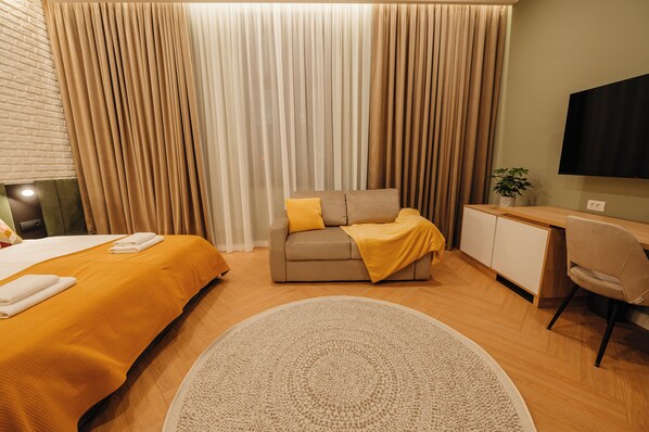 A hotel room with a bed, a sofa, a desk, and a television. - Villa Botar (Cluj-Napoca)