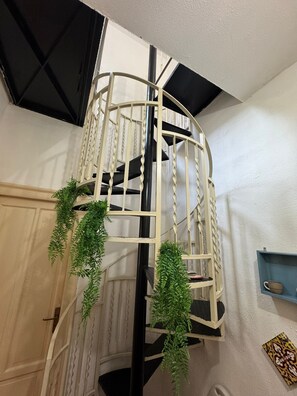 A spiral staircase with a white railing and black steps, surrounded by greenery. - Petit  Charme, tra Massimo e Politeama (Palermo)