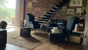 Ein rustikales Interieur mit einer Holztreppe, Ledersofas und einer großen Karte an der Wand.