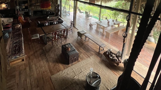 Ein geräumiges Zimmer mit hoher Decke, Holzbalken, einem großen Fenster und einer gemütlichen Sitzecke mit Kamin.