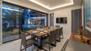 Un espace repas moderne avec une grande table en bois, dressée pour six personnes, entourée de chaises en osier.