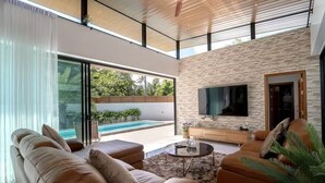 Un salon moderne avec une piscine, des canapés en cuir, un téléviseur et un mur en pierre.