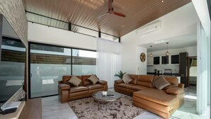 Un salon spacieux avec deux canapés en cuir, une table basse et une grande porte vitrée donnant sur un balcon.
