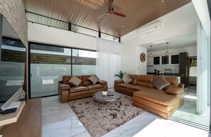 Ein geräumiges Wohnzimmer mit zwei Ledersofas, einem Couchtisch und einer großen Glasdoor, die auf einen Balkon führt.