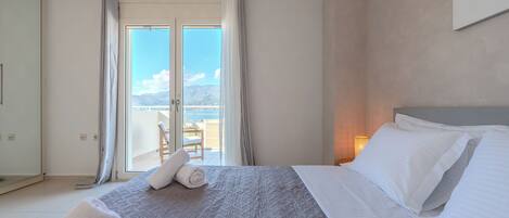 Une chambre d’hôtel avec un lit, une vue sur la mer et un balcon équipé d’une chaise.