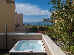 Ein Whirlpool auf einem Balkon mit Blick auf Meer und Berge.