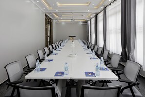 A conference room with a long table, chairs, water bottles, and a projector screen. - BEAL MALL AND HOTEL (Arua)