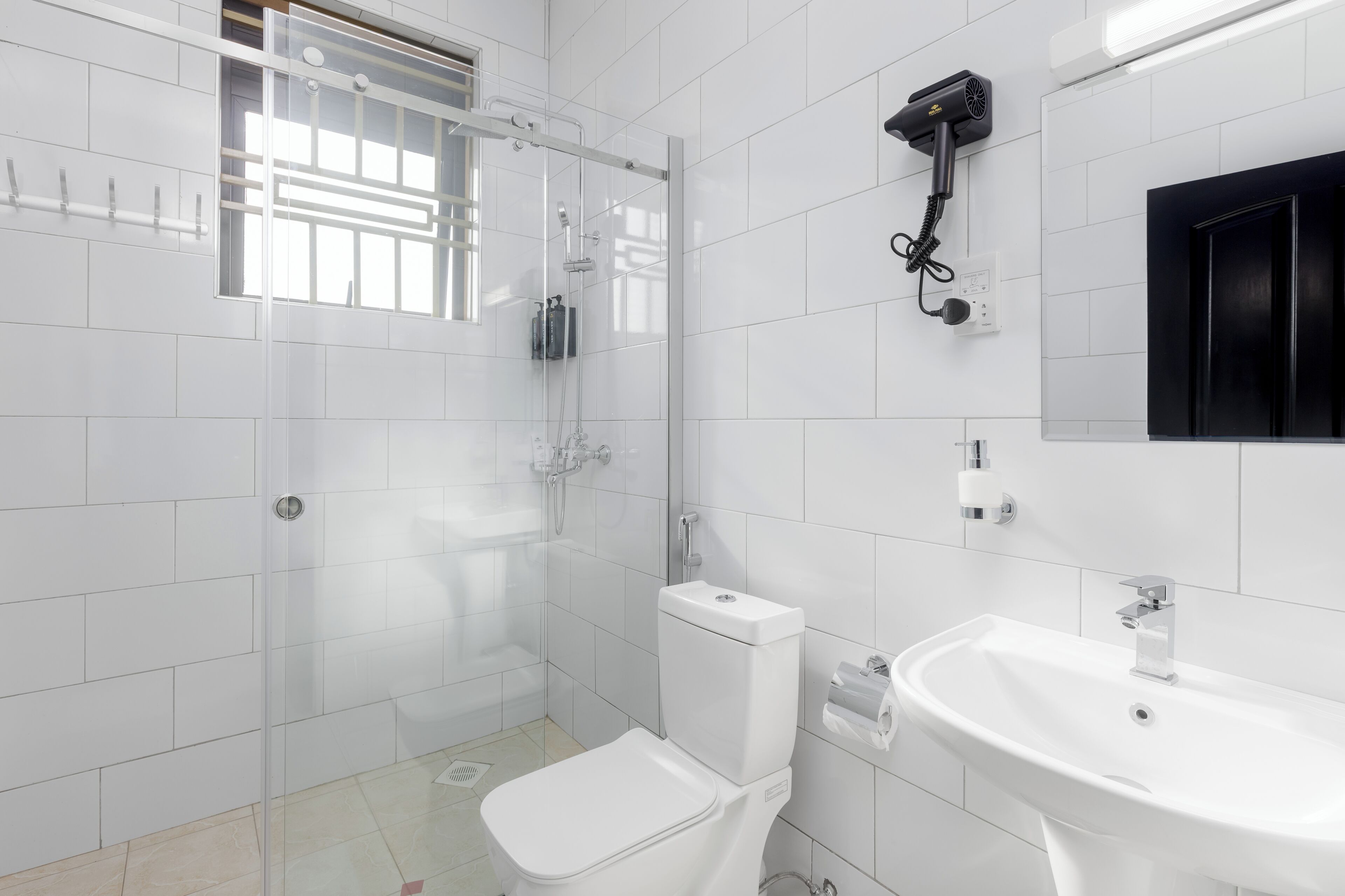 Uma casa de banho moderna com chuveiro de cabine de vidro, sanita branca, lavatório e espelho.
