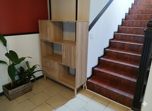 A staircase with wooden steps and a light wooden bench with multiple shelves.