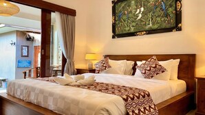 A well-appointed hotel room with a large bed, a painting of birds and foliage, and a view of the outdoor area. - Anugrah Twin Ubud (Ubud)