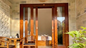 A wooden door with the number 4, leading to a room with a bed, a bedside table, and a chair. - Anugrah Twin Ubud (Ubud)