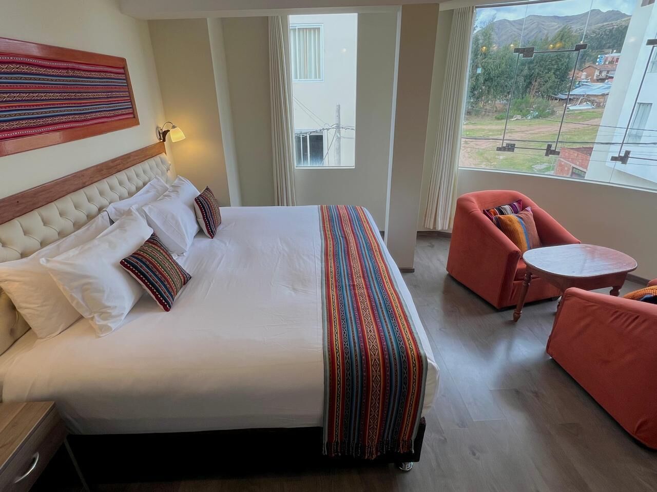 A hotel room with a large bed, a view of the outdoors, and a seating area with a table.
