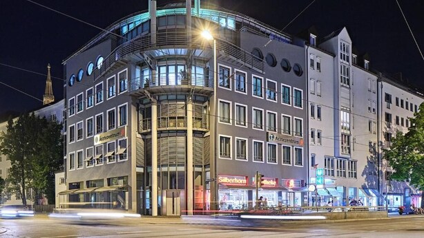Ein modernes Gebäude mit einer geschwungenen Fassade, zahlreichen Fenstern und einem markanten Eingang.