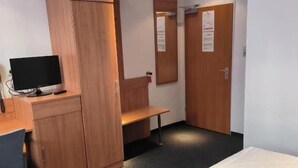 Ein Hotelzimmer mit Bett, Schreibtisch mit Computer, Kleiderschrank und Spiegel.