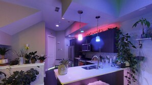 A modern kitchen with a central island, built-in appliances, and various potted plants.