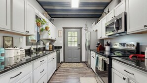 Una cocina con armarios blancos, encimera negra y suelo de madera.