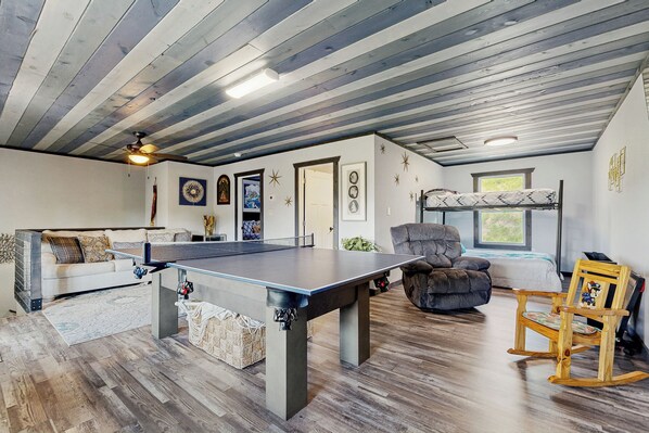 A spacious room with a ping pong table, a sofa, a rocking chair, and a ceiling fan. - 1 Mi to Douglas Lake! Mtn-view Haven w/ Hot Tub (Sevierville)