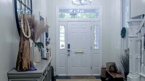 A hallway with a white door, a wooden cabinet, a rug, and a staircase. - 4 BR Home w/ Modern Comforts & Park View (Savannah)