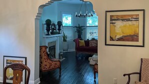 A living room with a fireplace, a red sofa, and a large painting on the wall. - 4 BR Home w/ Modern Comforts & Park View (Savannah)