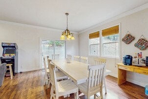 A dining area with a wooden table and chairs, a chandelier, and a coffee station.