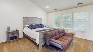 Ein Schlafzimmer mit Bett, Nachttisch und einem großen Fenster.