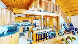 A spacious kitchen with wooden cabinets, a central island, and a dining area with bar stools. - Hot Tub, Lake Views! All-season Hinsdale Haven (Hinsdale)