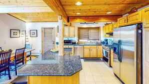 A kitchen with wooden cabinets, a granite countertop, stainless steel appliances, and a dining area with chairs and a table. - Hot Tub, Lake Views! All-season Hinsdale Haven (Hinsdale)