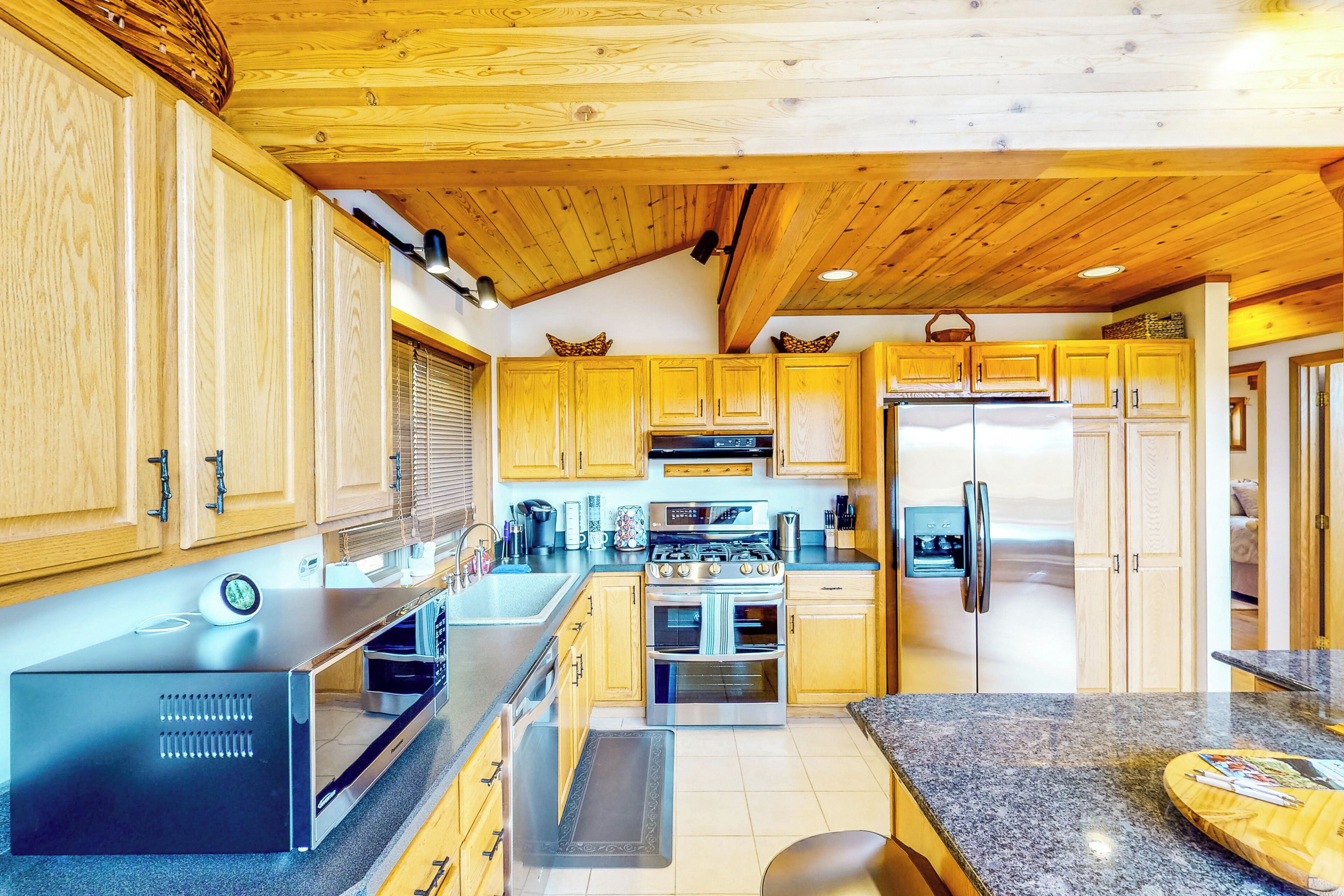 Una cucina moderna con mobili in legno, elettrodomestici in acciaio inossidabile e un piano di lavoro in granito.
