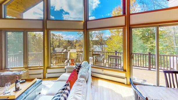 A spacious room with large windows, a wooden ceiling, and a view of a deck and trees. - Hot Tub, Lake Views! All-season Hinsdale Haven (Hinsdale)