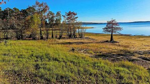 A grassy area with trees and a body of water in the background. - 2BR Dog-friendly Home Near Lake w/ Fire Pit (San Augustine)