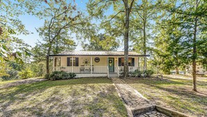 A two-story house with a front porch, a stone pathway leading to the entrance, and a well-maintained lawn. - 2BR Dog-friendly Home Near Lake w/ Fire Pit (San Augustine)