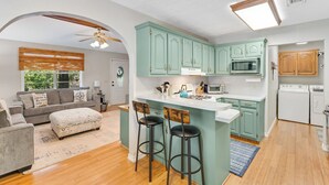 A modern kitchen with teal cabinets, a central island with stools, a microwave, and a dishwasher. - 2BR Dog-friendly Home Near Lake w/ Fire Pit (San Augustine)
