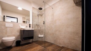 Une salle de bain moderne avec une douche à parois de verre, des toilettes blanches et un lavabo doté d’un porte-serviettes.