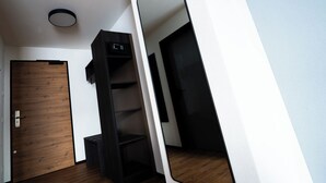 Une pièce moderne et compacte, dotée d’une porte en bois, d’une étagère noire et d’un mur blanc.