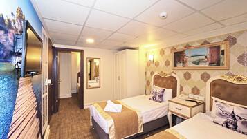 A hotel room with two beds, a television, a mirror, a painting, and a ceiling light.