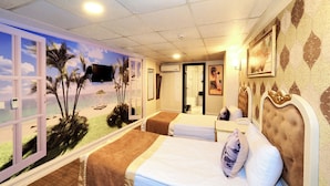 A hotel room with a beach mural, a bed, a bedside table, a TV, and a bathroom door. - ELYSİON HOTEL (İstanbul)