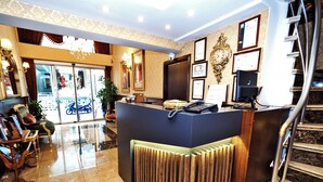 A hotel reception area with a modern counter, a staircase, and a view of the street outside. - ELYSİON HOTEL (İstanbul)
