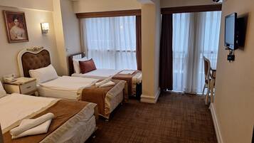 Habitación de hotel con dos camas, una mesita de noche con lámpara, un cuadro en la pared y un televisor también en la pared.
