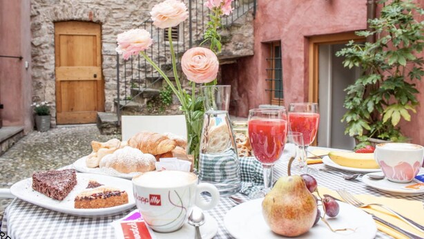 A table set with pastries, a glass of red juice, and a pear. - Alla torre del barbarossa B&B Foresteria (Maggiana)