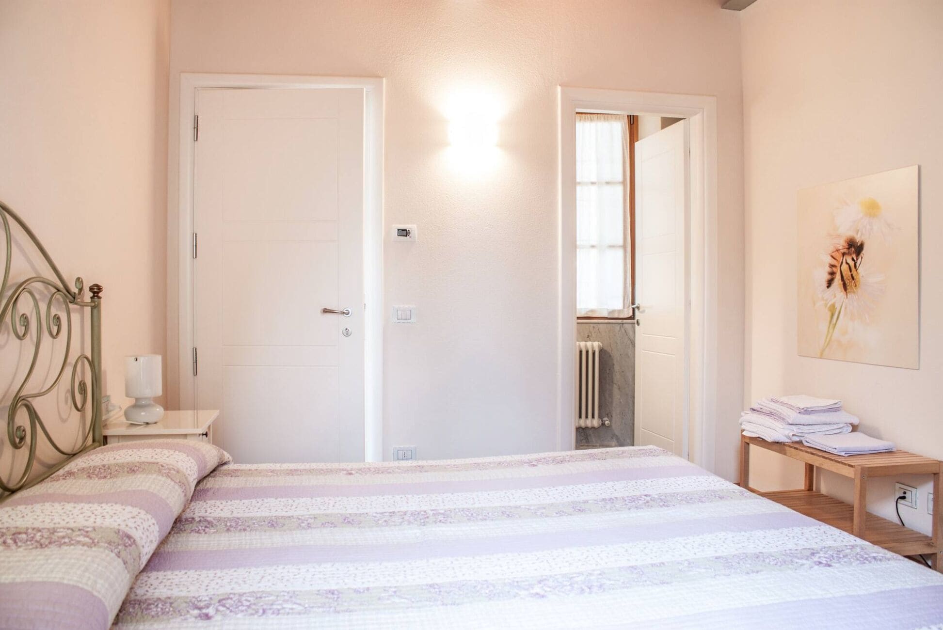 Une chambre à coucher avec un lit, une table de chevet, un radiateur et une porte.