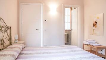 Une chambre à coucher avec un lit, une table de chevet, un radiateur et une porte.