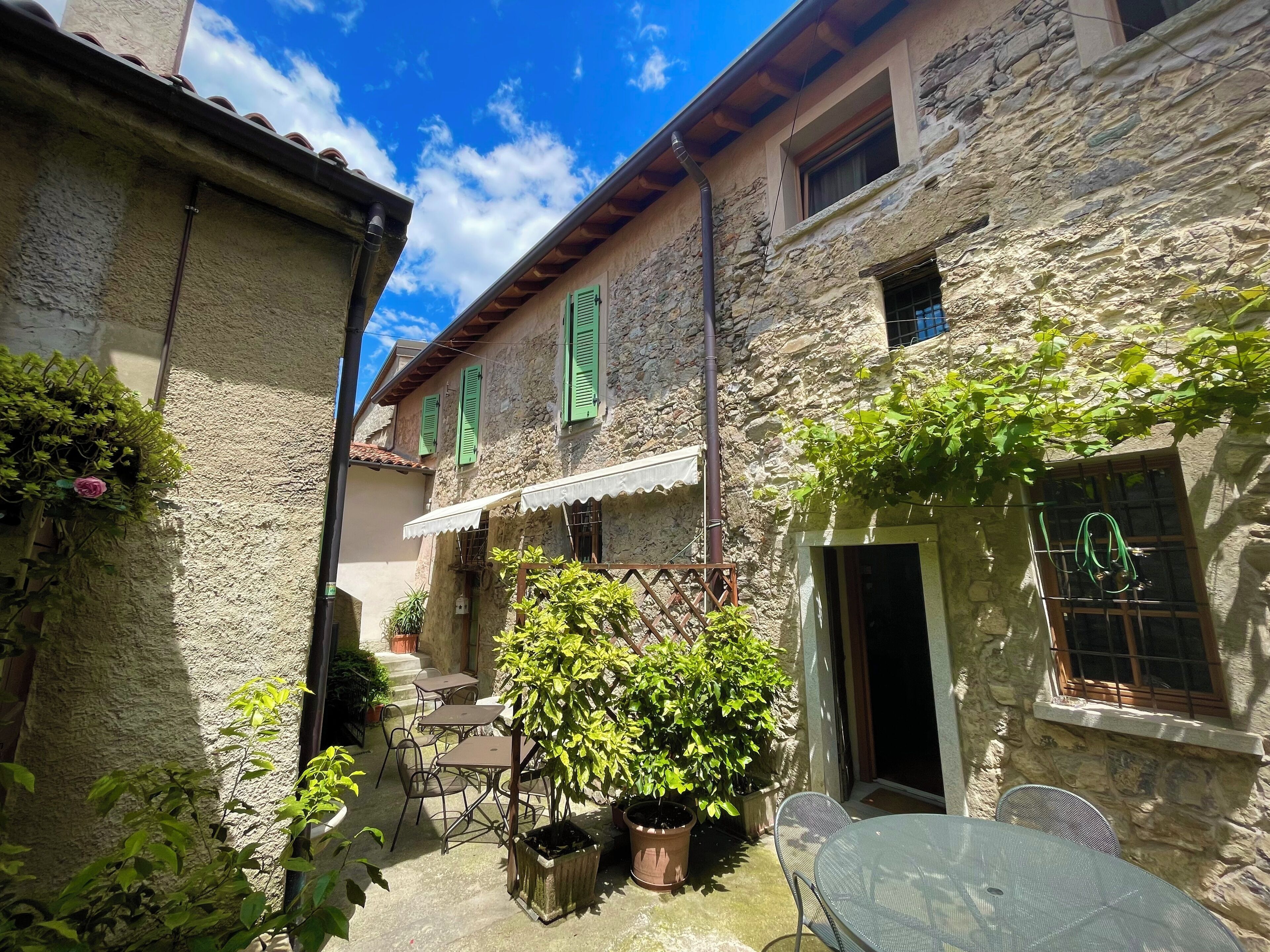 A courtyard with stone buildings, outdoor seating, and potted plants.