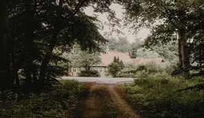 Ein Landhaus mit rotem Dach, umgeben von üppigem Grün und Bäumen.